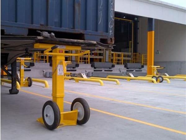 Yellow mobile trailer stand supporting the front of a blue shipping container.